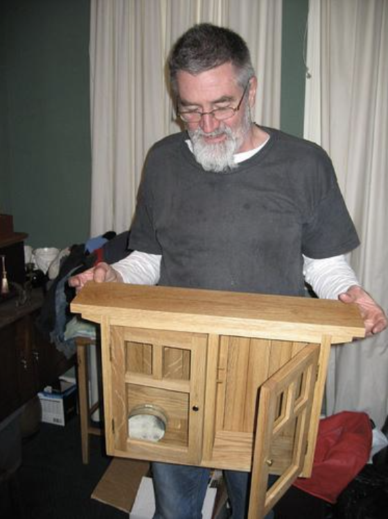 A man holding a small wooden cabinet